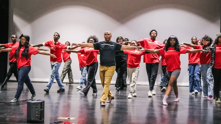 A line of dancers in red shirts.